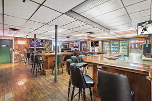 Bar with a dry bar, a drop ceiling, hardwood / wood-style floors, and visible vents