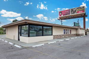 Exterior space with parking, stone siding, and stucco siding