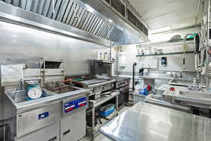 Kitchen featuring wall chimney exhaust hood and stainless steel countertops