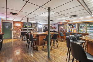 Bar with a dry bar, a drop ceiling, and hardwood / wood-style floors