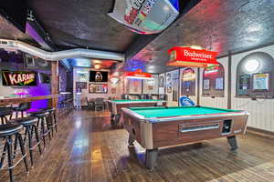 Game room featuring pool table, a dry bar, and hardwood / wood-style flooring