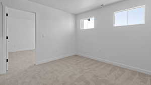 Empty room with light colored carpet, baseboards, visible vents, and a textured ceiling