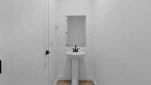 Bathroom featuring baseboards, a sink, and wood finished floors