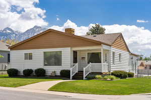 Bungalow with a shingled roof, a mountain view, a front yard, and a chimney