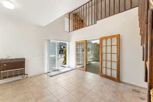 Entryway featuring baseboards, tile patterned flooring, and a towering ceiling
