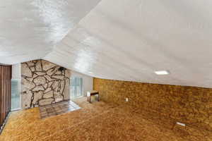Additional living space featuring a textured ceiling and lofted ceiling