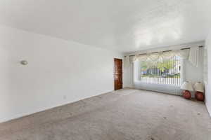 Unfurnished living room with baseboards and light colored carpet
