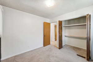 Unfurnished bedroom with carpet flooring, a textured ceiling, visible vents, and a closet