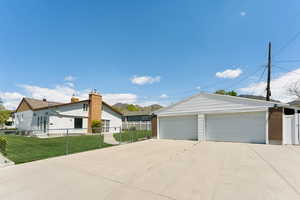Ranch-style home with a front yard, a detached garage, brick siding, fence, and an outdoor structure