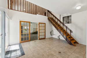 Interior space with light tile patterned floors, plenty of natural light, french doors, and stairs