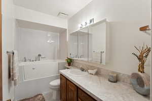 Bathroom with toilet, visible vents, a bathtub, and vanity
