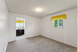 Spare room featuring baseboards, a textured ceiling, and carpet