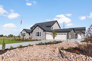 View of front facade with a garage, stone siding, and concrete driveway