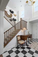 Stairs with a healthy amount of sunlight, baseboards, visible vents, and a towering ceiling