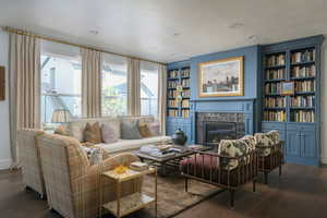 Living area featuring a textured ceiling, dark wood-style flooring, a wealth of natural light, and a premium fireplace