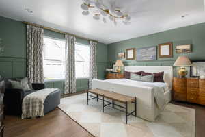 Bedroom with wainscoting, a decorative wall, and wood finished floors