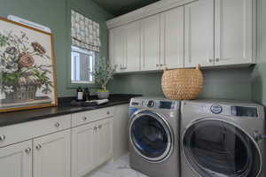Washroom featuring marble finish floor, cabinet space, and washing machine and clothes dryer