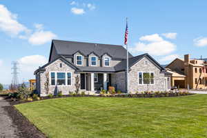 View of front facade featuring a front yard and stone siding
