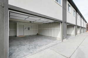 Garage with driveway, a garage door opener, and electric panel