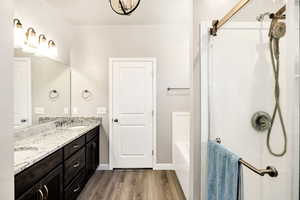 Full bath with a sink, double vanity, walk in shower, and wood finished floors