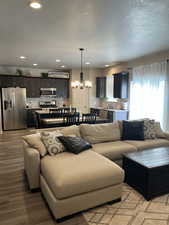 Living room with light wood-style floors, recessed lighting, a textured ceiling, and a notable chandelier