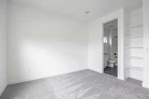 Unfurnished bedroom featuring baseboards, carpet, and ensuite bathroom