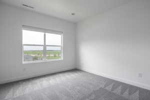 Carpeted spare room with baseboards and visible vents