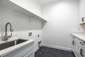 Clothes washing area with cabinet space, washer hookup, a sink, baseboards, and electric dryer hookup