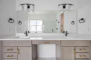 Bathroom featuring double vanity, a sink, marble finish floor, and a shower stall