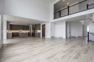 Unfurnished living room with visible vents and a towering ceiling
