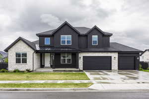 Craftsman inspired home featuring covered porch, board and batten siding, a front yard, concrete driveway, and stone siding