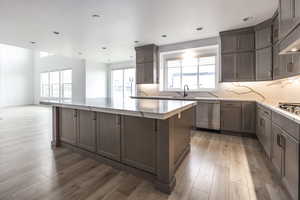 Kitchen featuring light wood-type flooring, appliances with stainless steel finishes, backsplash, and a center island
