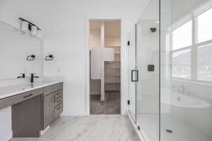 Full bath with vanity, marble finish floor, a walk in closet, and a shower stall
