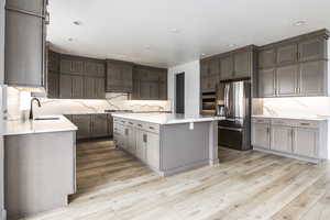 Kitchen featuring a kitchen island, appliances with stainless steel finishes, a sink, and light wood-style floors