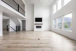 Unfurnished living room with baseboards, a high ceiling, and light wood-style flooring