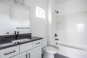 Full bath with vanity, tile patterned floors, toilet, and tub / shower combination