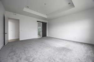 Unfurnished bedroom with visible vents, a barn door, carpet floors, and a tray ceiling
