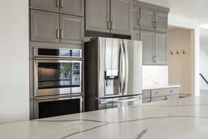 Kitchen with stainless steel appliances, light stone counters, and gray cabinets