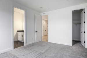 Unfurnished bedroom with visible vents, carpet flooring, baseboards, and a walk in closet