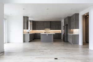 Kitchen featuring freestanding refrigerator, a kitchen island, light wood-style flooring, and light countertops