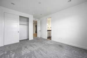 Unfurnished bedroom featuring connected bathroom, carpet floors, baseboards, visible vents, and a closet