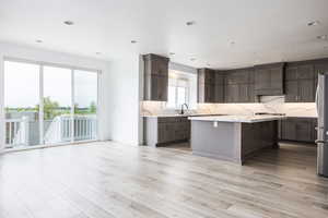 Kitchen with light wood-style floors, recessed lighting, a center island, appliances with stainless steel finishes, and backsplash