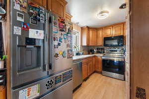 Kitchen with tasteful backsplash, a sink, light countertops, light wood-style floors, and stainless steel appliances