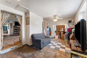 Living area featuring attic access, a ceiling fan, concrete floors, and visible vents
