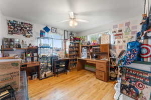 Office with light wood-style floors and a ceiling fan