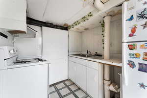 Kitchen featuring white appliances, light floors, light countertops, white cabinetry, and a sink