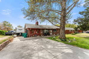 Ranch-style home featuring a front yard, roof with shingles, a chimney, brick siding, and driveway