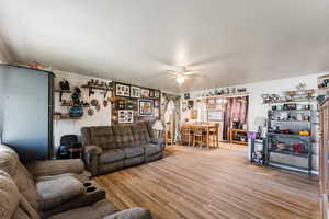 Living room with ornamental molding, light wood-style flooring, and ceiling fan