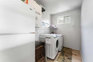 Washroom featuring laundry area, washing machine and dryer, and wood finished floors