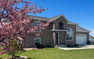 Traditional home featuring an attached garage, roof with shingles, driveway, and a front yard